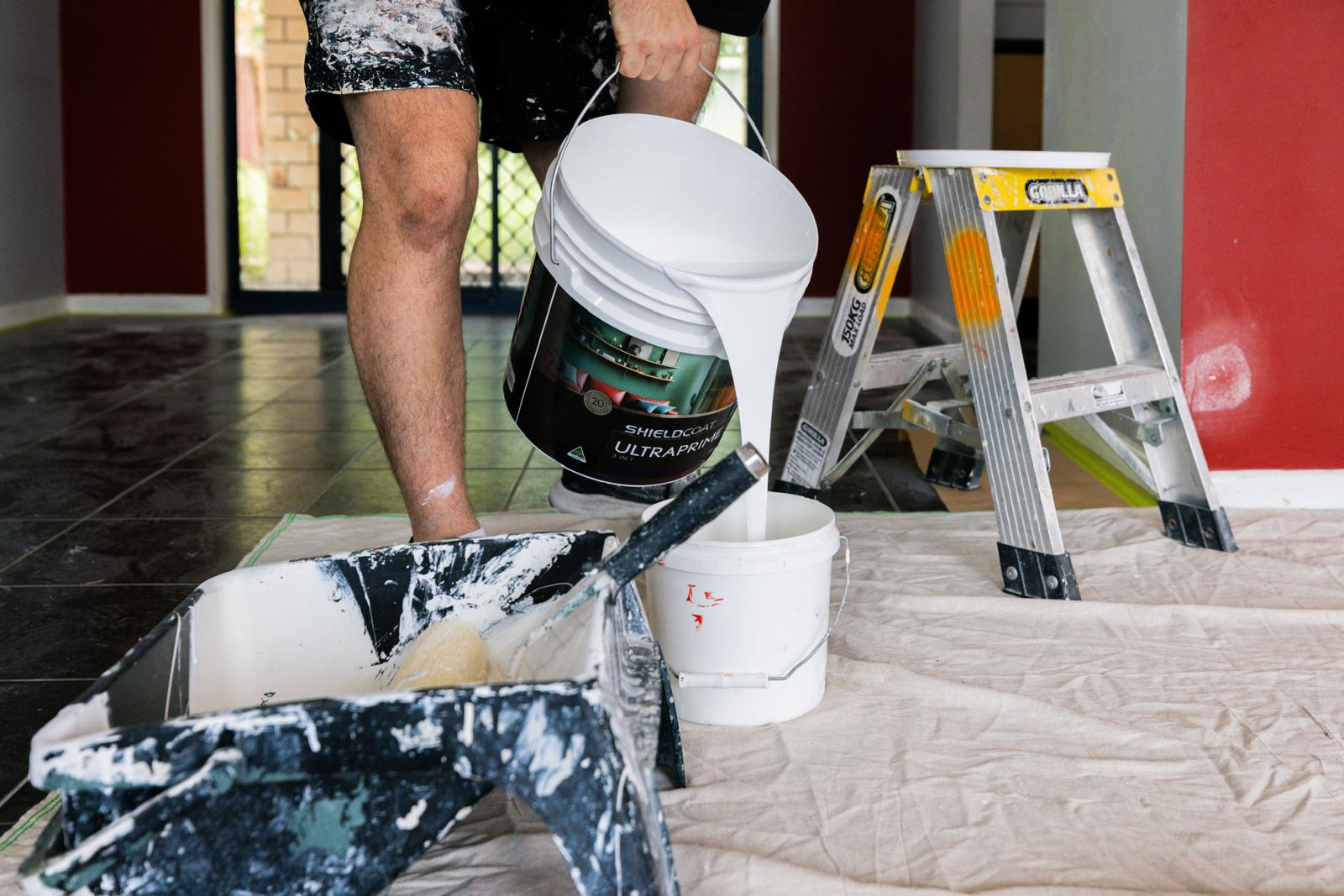 Pouring premium Shieldcoat Ultraprime paint into a professional tray on a protected south-east Queensland worksite